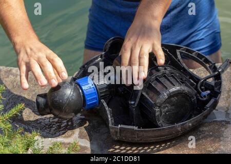 Reparatur der Wasserpumpe für einen kleinen Zierteich mit Springbrunnen Stockfoto