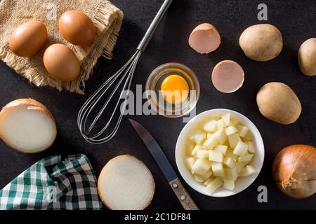 Spanische Omelette Tortilla Zutaten: Eier, Kartoffeln und Zwiebeln auf schwarzem Schiefer Hintergrund Stockfoto