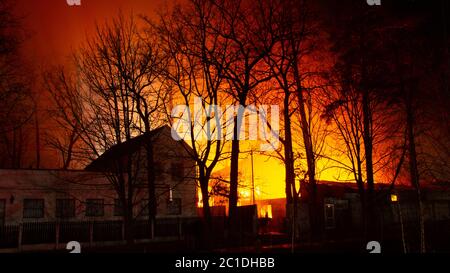 Brand im Fabrikgebäude bei Nacht. Feuerwehrleute versuchen, das Feuer zu löschen Stockfoto