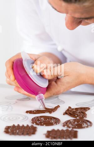 Koch macht Figuren mit Schokolade zu einem Kuchen schmücken Stockfoto