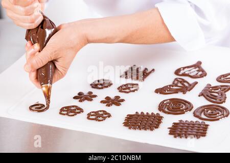 Koch macht Figuren mit Schokolade zu einem Kuchen schmücken Stockfoto