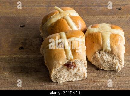 Heiße Kreuz-Brötchen auf rustikalem Holztisch aus der Nähe Stockfoto