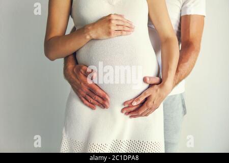 Junger Mann und hübsche schwangere Frau umarmen zusammen Stockfoto