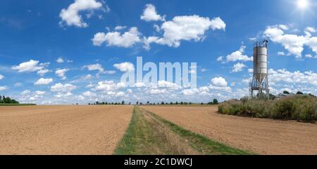 Frisch gedroschene Felder mit braunem Boden an einem Silo in der Sonne Stockfoto