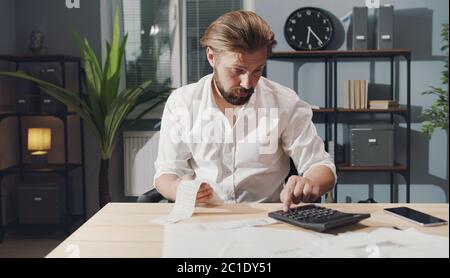 Geschäftsmann, der Zahlen auf dem Rechner überprüft Stockfoto