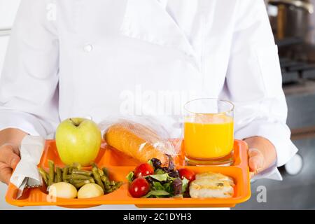 Kochen Sie in einer Schule mit einem Tablett von Lebensmitteln Stockfoto