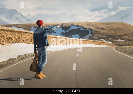 Tourismus und Menschen Konzept - stilvolle Hipster zu Fuß entlang Landstraße im Freien und zeigt Finger auf etwas Stockfoto