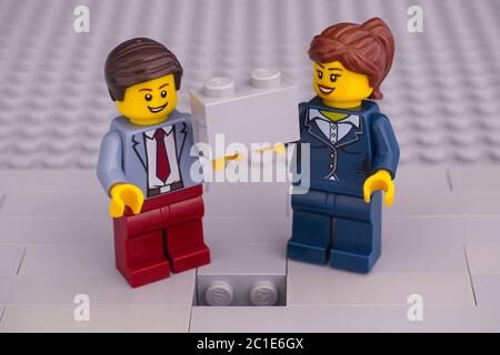 Tambow, Russische Föderation - 07. Juni 2020 Lego Geschäftsmann und Geschäftsfrau minifiguren mit Ziegel bereit, die Fertigstellung graue Hauswand Stockfoto