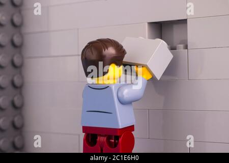 Tambow, Russische Föderation - 07. Juni 2020 Lego man minifigur mit Ziegel bereit, die graue Wand zu beenden Stockfoto