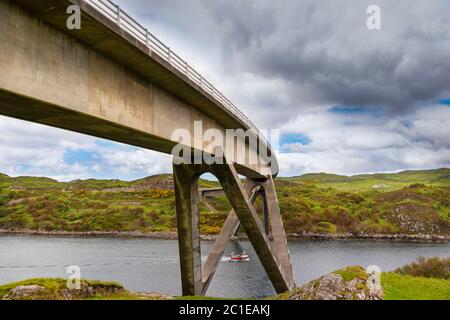 KYLESKU BRÜCKE SUTHERLAND SCHOTTLAND ÜBER LOCH CAIRNBAWN MIT ROTEM FISCHERBOOT UNTER DEM BOGEN Stockfoto