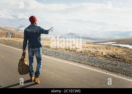 Tourismus und Menschen Konzept - stilvolle Hipster zu Fuß entlang Landstraße im Freien und zeigt Finger auf etwas Stockfoto