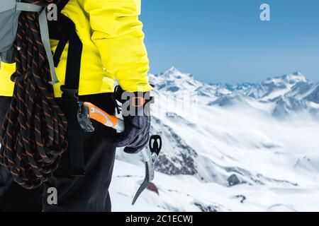 Ein Bergsteiger hält eine Eispickel hoch in den schneebedeckten Bergen. Nahaufnahme von hinten. Outdoor extreme Outdoor Climbin Stockfoto