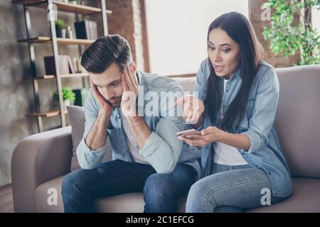 Foto von zwei Menschen frustriert Frau verwenden Smartphone suchen sms finden eine andere Frau Nachricht Punkt Hand schockiert Mann sitzen Komfort gemütliche Couch müde Stockfoto