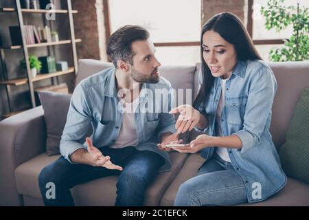 Foto von zwei Personen Frau verwenden Smartphone versuchen erklären Neid wütend Ehemann sie nicht haben einen anderen Mann Punkt Hand Bildschirm Gefühl verwirrt sitzen Komfort gemütlich Stockfoto