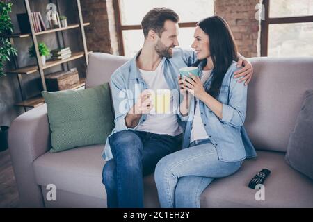 Portrait von leidenschaftlichen fürsorglich verheiratet Paar sitzen Couch Mann Frau Umarmung trinken Getränk Tasse genießen zusammen Freizeit im Haus drinnen Stockfoto