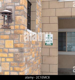 Quadratischer Rahmen Außenansicht der Apartments mit Rauchverbot-Schild an der Steinmauer Stockfoto