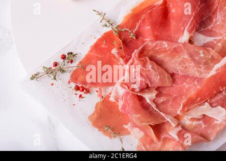 Draufsicht auf Schinken mit Thymian und rosa Pfeffer auf Backpapier Stockfoto