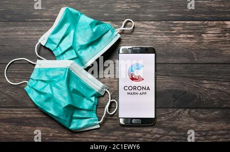 Coronavirus Warn App für COVID-19 Kontaktverfolgung mit chirurgischen Gesichtsmasken auf Holzoberfläche - Pandemisches Containment Konzept Stockfoto