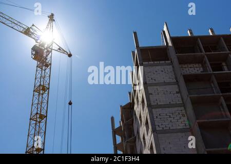 Baustelle mit Kranen auf einem Hintergrund von blauem Himmel. Das Konzept der Errichtung monolithischer Hochhäuser Stockfoto