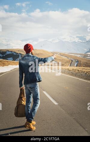 Tourismus und Menschen Konzept - stilvolle Hipster zu Fuß entlang Landstraße im Freien und zeigt Finger auf etwas Stockfoto