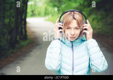 Portrait eines attraktiven Sportmädchen blond in einer leichten Jacke unten Dressing bluetooth Kopfhörer mit Musik oder der Soun Stockfoto