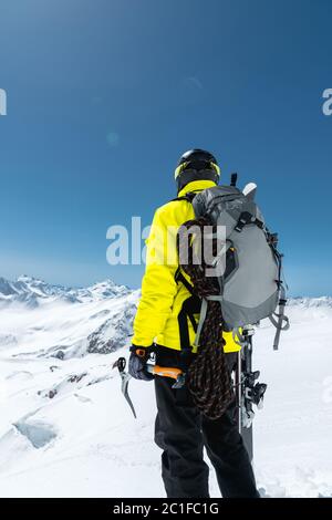 Ein Bergsteiger hält eine Eispickel hoch in den schneebedeckten Bergen. Blick von hinten. Outdoor Extremklettern im Freien Stockfoto