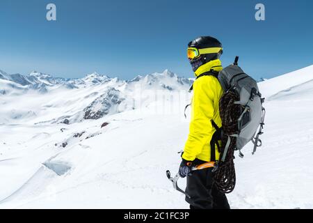 Ein Bergsteiger hält eine Eispickel hoch in den schneebedeckten Bergen. Blick von hinten. Outdoor Extremklettern im Freien Stockfoto