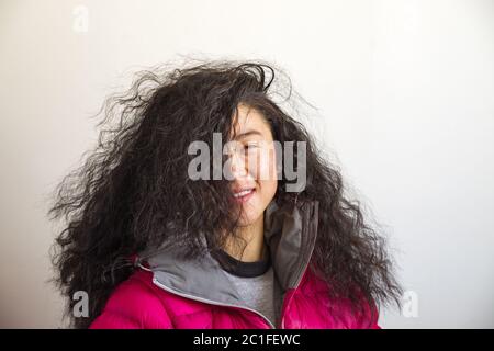 asiatische Frau mit verrückten großen welligen Haar bedeckt die Hälfte ihres Gesichts Stockfoto