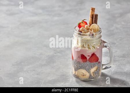 Bananen Smoothie mit Chia Samen und Erdbeer Joghurt im Glas Marmeladenglas auf einen konkreten Hintergrund Stockfoto
