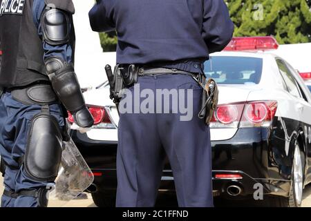 Rückansicht von japanischen Polizisten mit Streifenwagen Stockfoto