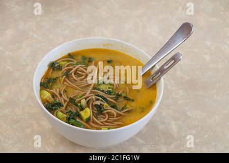 Schüssel mit hausgemachter Suppe mit reichhaltigem Brühgemüse und Soba-Nudeln Stockfoto