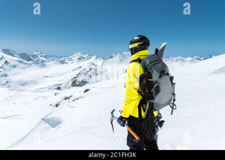 Ein Bergsteiger hält eine Eispickel hoch in den schneebedeckten Bergen. Blick von hinten. Outdoor Extremklettern im Freien Stockfoto