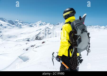 Ein Bergsteiger hält eine Eispickel hoch in den schneebedeckten Bergen. Blick von hinten. Outdoor Extremklettern im Freien Stockfoto