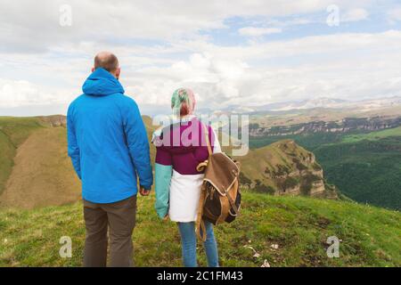 Ein Paar Hipster-Touristen steht nebeneinander in den Bergen vor der Kulisse der Hochebene aus Tälern und sk Stockfoto