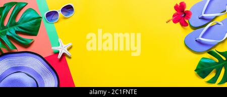 Flip-Flops und Hut und tropische Blätter - Strandzubehör im Minimal Colorful Design Stockfoto