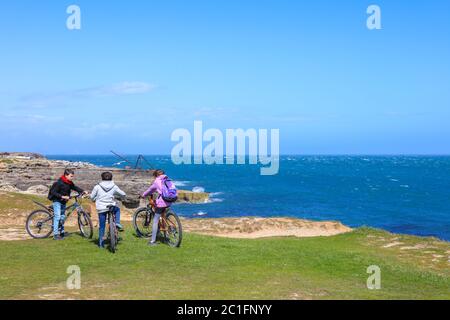 Isle of Portland, Dorset / Großbritannien - 23. Mai 2020: Drei Teenager mit Mountainbike am Klippenrand mit blauem Himmel und Horizont über dem Wasser. Stockfoto