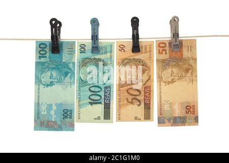 Brasilianische Real Banknoten in einer Wäscheleine - Geldwäsche - schmutziges Geld Konzept - isoliert in weißem Hintergrund Stockfoto