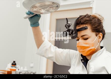 Zahnarzt junge Frau behandelt einen Patienten einen Mann. Der Arzt verwendet Einweghandschuhe, eine Maske und einen Hut. Der Zahnarzt arbeitet im Mund des Patienten, verwendet ein Stockfoto