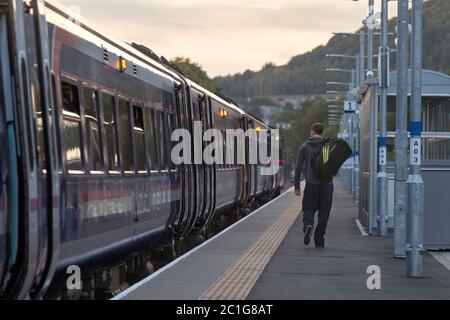 Eineineinreisende Eisenbahner, die am Tweedbank Bahnhof auf der Grenzbahnlinie in Schottland entlang der Plattform laufen und einen Scotrail Zug warten Stockfoto
