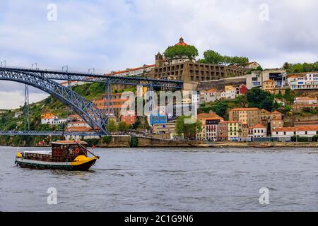 Blick über den Douro Fluss und die Dom Luis I Brücke in Vila Nova de Gaia und Touristenboote, die für den Transport von Portwein in Porto, Portugal, verwendet wurden Stockfoto