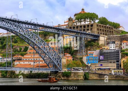 Porto, Portugal - Mai 30 2018: Blick über den Douro Fluss und die Brücke Dom Luis I auf Vila Nova de Gaia und traditionelle touristische Rabelo Boote Stockfoto