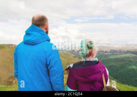 Ein Paar Hipster-Touristen steht nebeneinander in den Bergen vor der Kulisse der Hochebene aus Tälern und sk Stockfoto