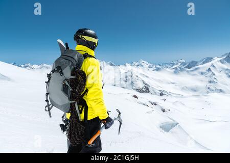 Ein Bergsteiger hält eine Eispickel hoch in den schneebedeckten Bergen. Blick von hinten. Outdoor Extremklettern im Freien Stockfoto