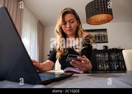 Junge Frau Eingabe von Kreditkarten-Informationen Online-Shopping aus dem Wohnzimmer. Vorderansicht. Niedriger Winkel. Stockfoto
