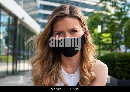 Hübsche blonde Frau trägt Schutzmaske Blick auf Kamera. Hochformat. Nahaufnahme. Im Freien. Stockfoto