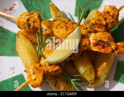 Marokkanisches Essen. Mariniertes Huhn mit Zitronenspieß und Rosmarin auf einem Bett mit Bratkartoffeln. Stockfoto