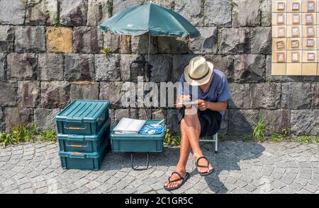 Mann mit Hutzeichnung an seinem Stand in Otaru, Hokkaido, Japan Stockfoto