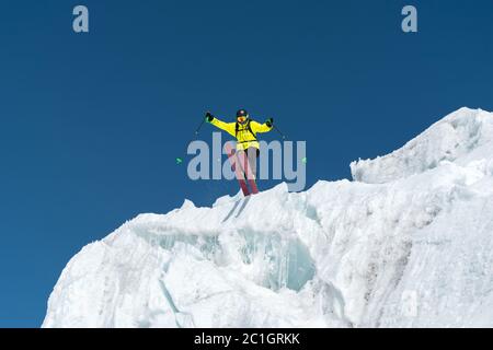 Ein springender Skifahrer, der von einem Gletscher gegen einen blauen Himmel hoch in den Bergen springt. Professionelles Skifahren Stockfoto