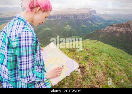 Mädchen Reisende mit bunten Haaren sitzen auf Natur-Karte lesen und halten einen Kompass in der Hand. Das Konzept der Navigation Th Stockfoto