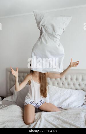 Junge Woomen im Bett mit Kissen. Glückliches Mädchen zu Hause. Gutes Schlafkonzept Stockfoto